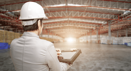 Energy auditor standing in warehouse with clipboard
