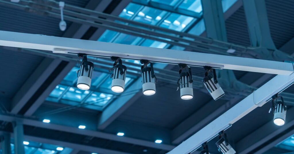 A warehouse’s skylight windows, where several LED lights are installed on a rail. The room is bathed in a blue glow.